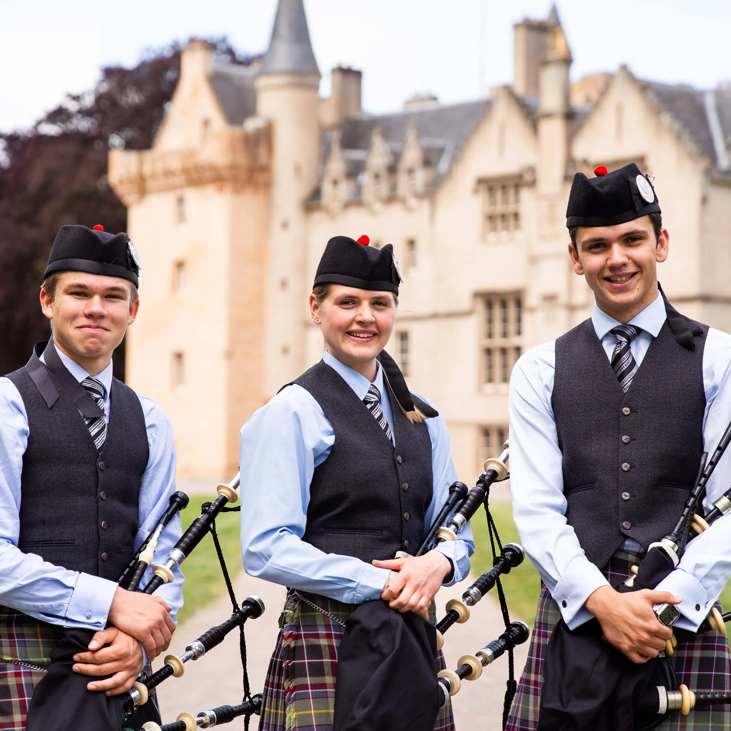 Three of Gordonstoun’s award winning pipe band members stand outside the front of Brodie castle before a performance.