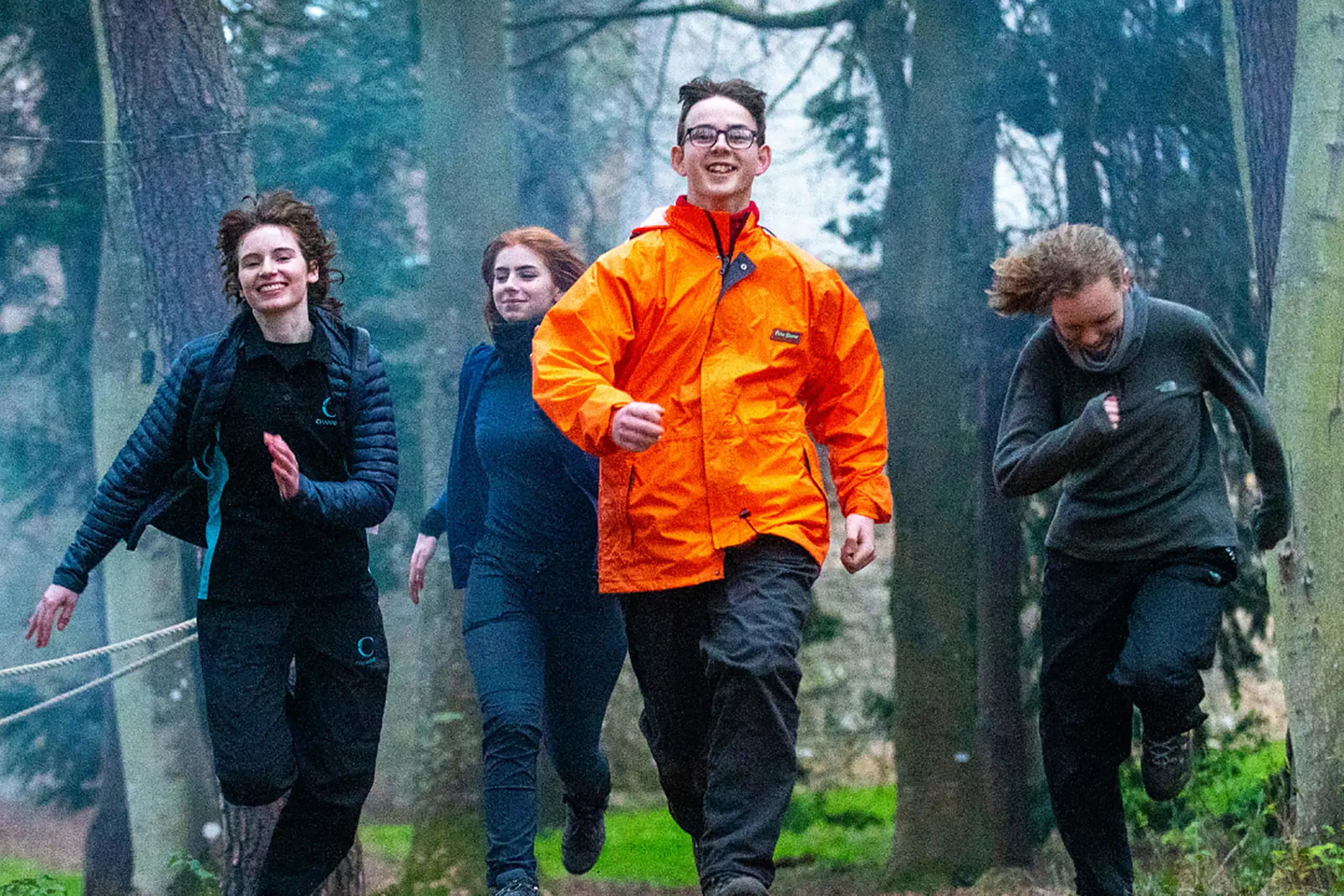 Students running through the woodland area