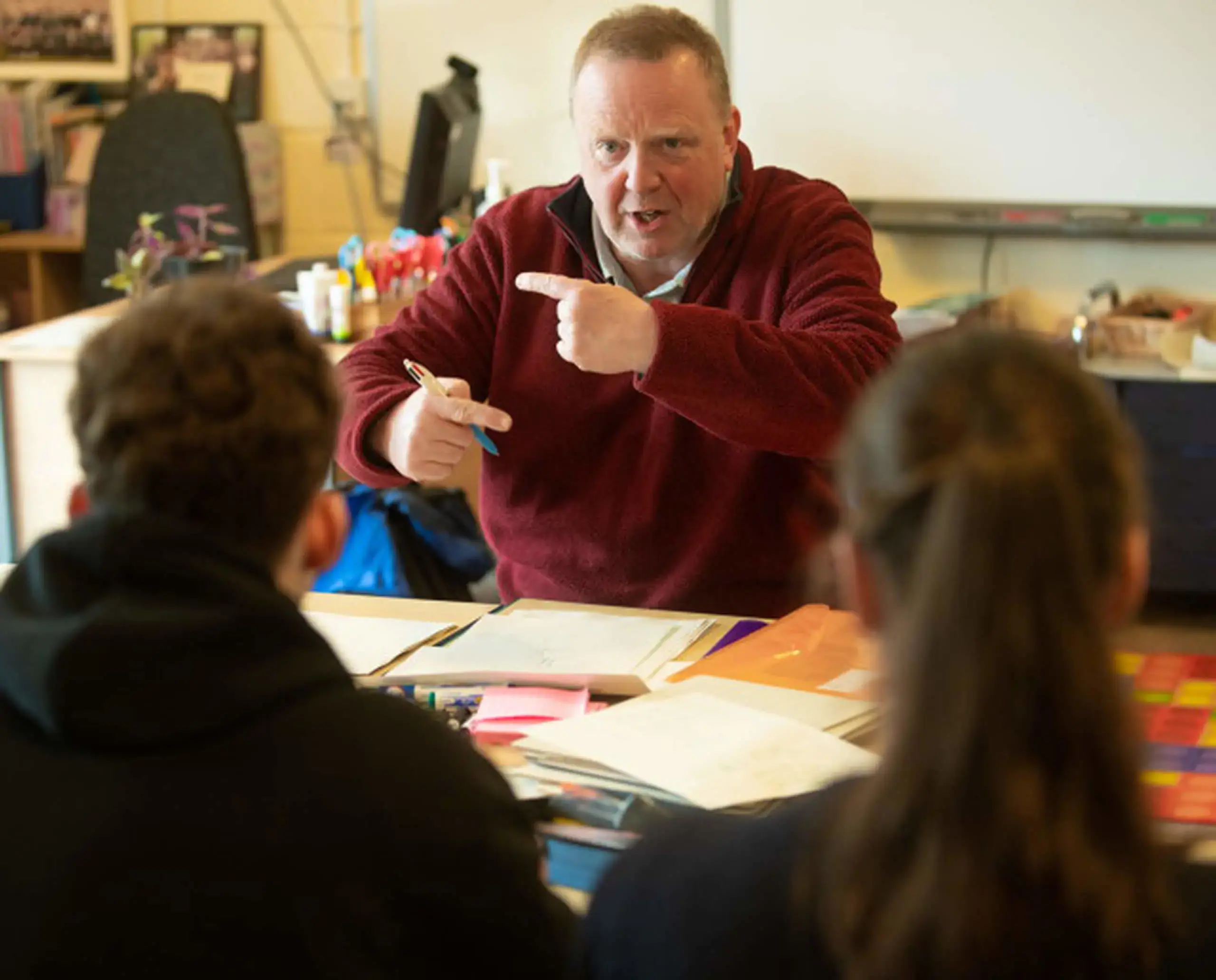 Expressive teacher explaining a concept to a small group of students on the Active Revision Course