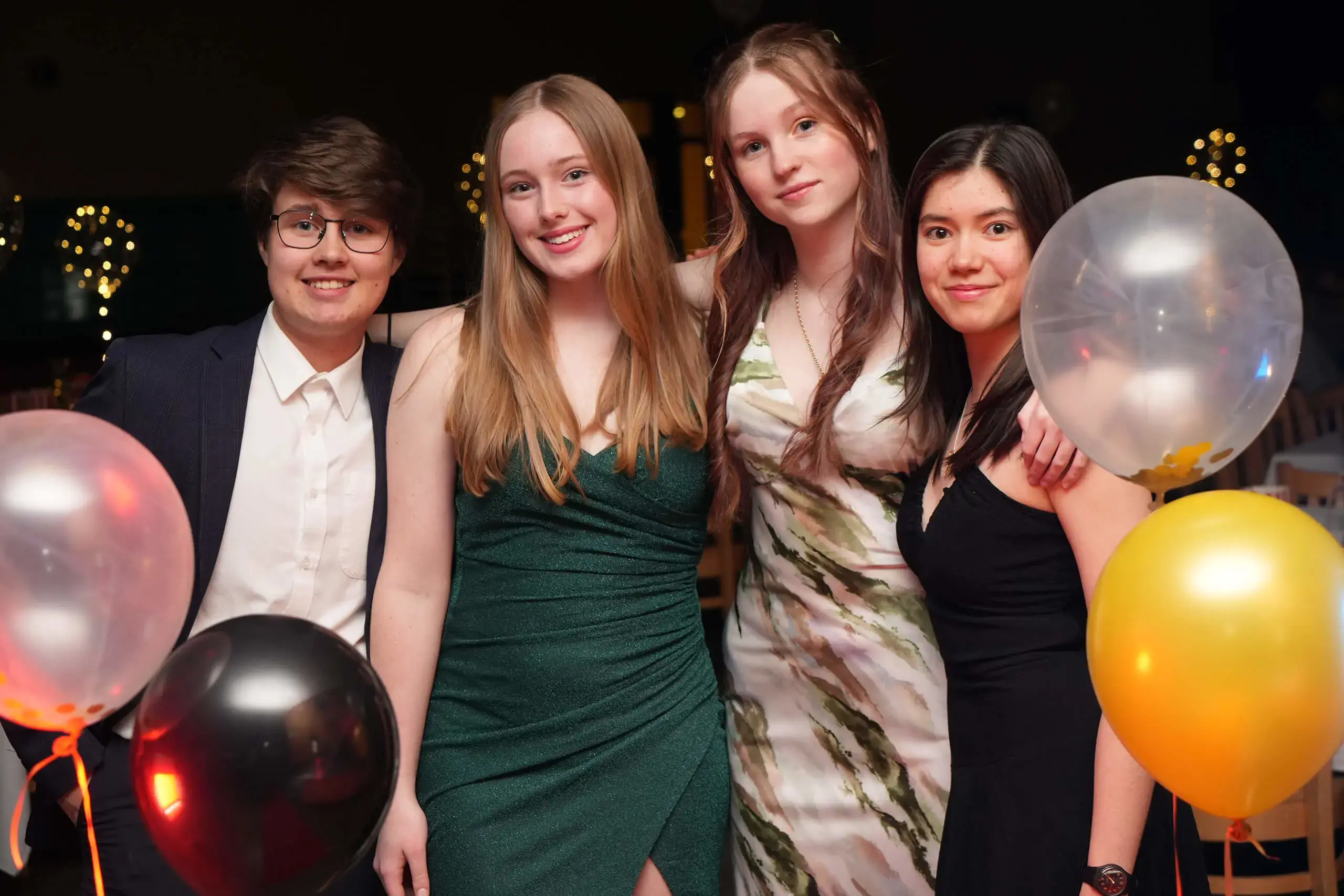 Students in evening dresses and suits smile at the camera during a media oscars social event.