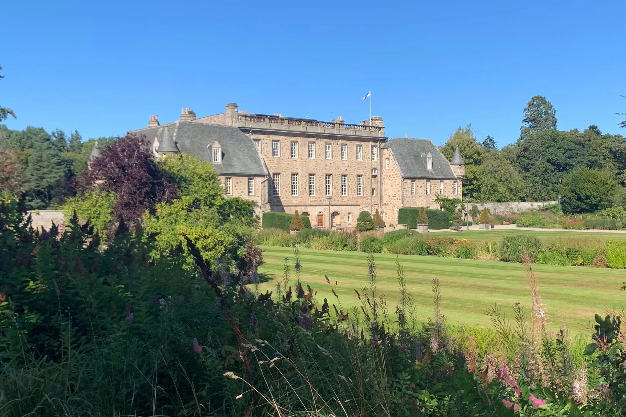 Gordonstoun House in the sunshine with the flag blowing in the wind.