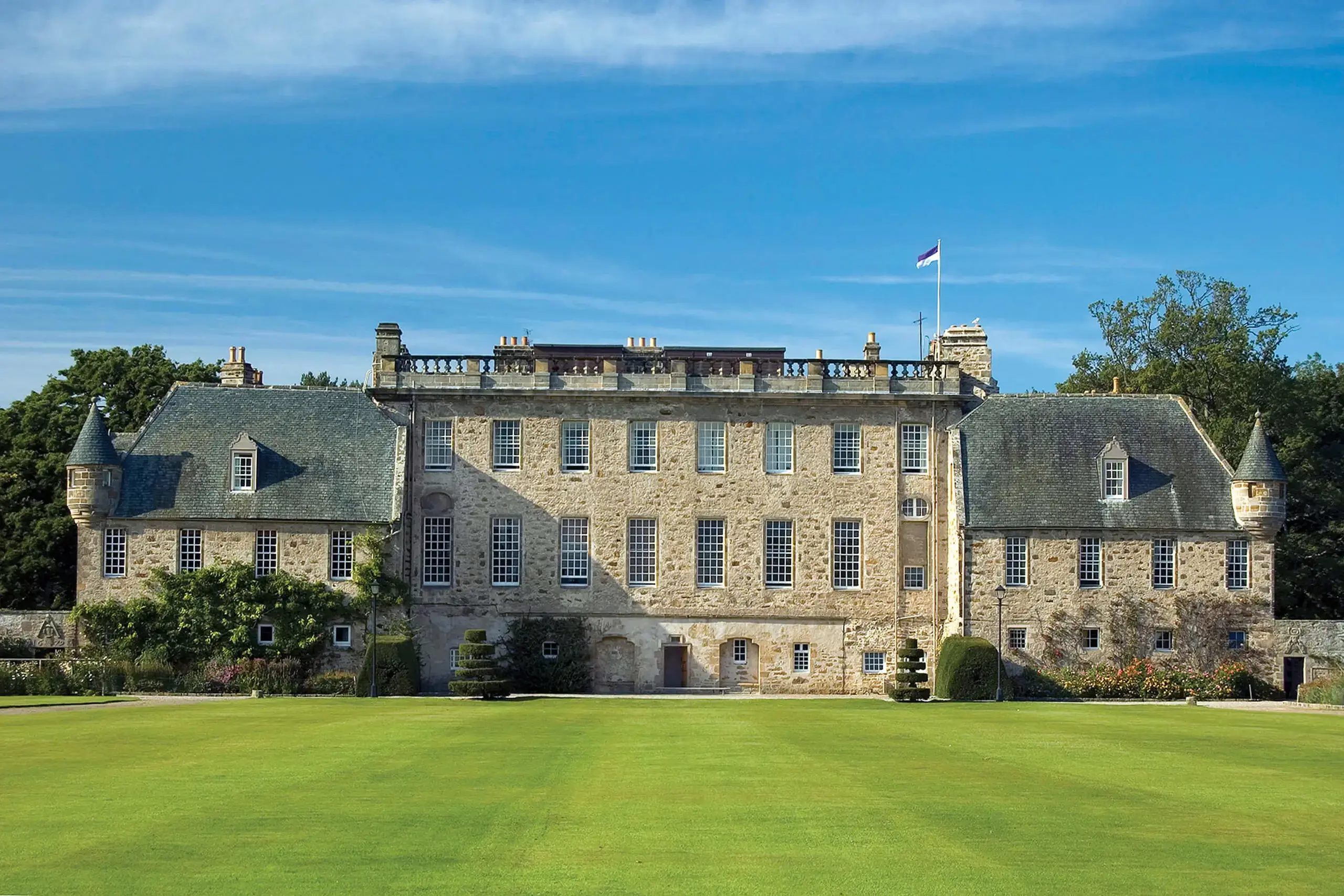 Gordonstoun House from the South Lawn with the school flag flying on a sunny blue sky day.