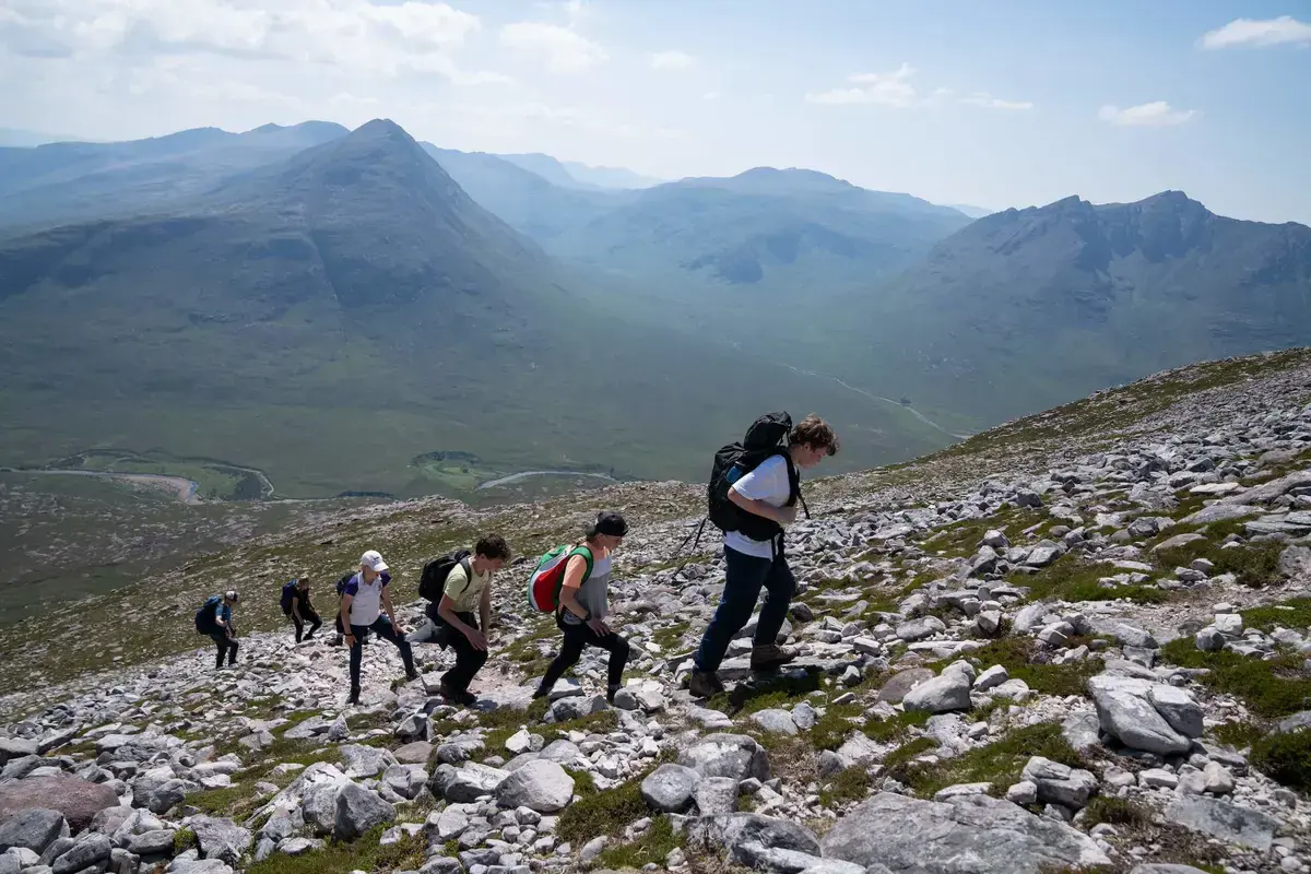 Gordonstoun students climbing a mountain in the Scottish Highlands in the sunshine.