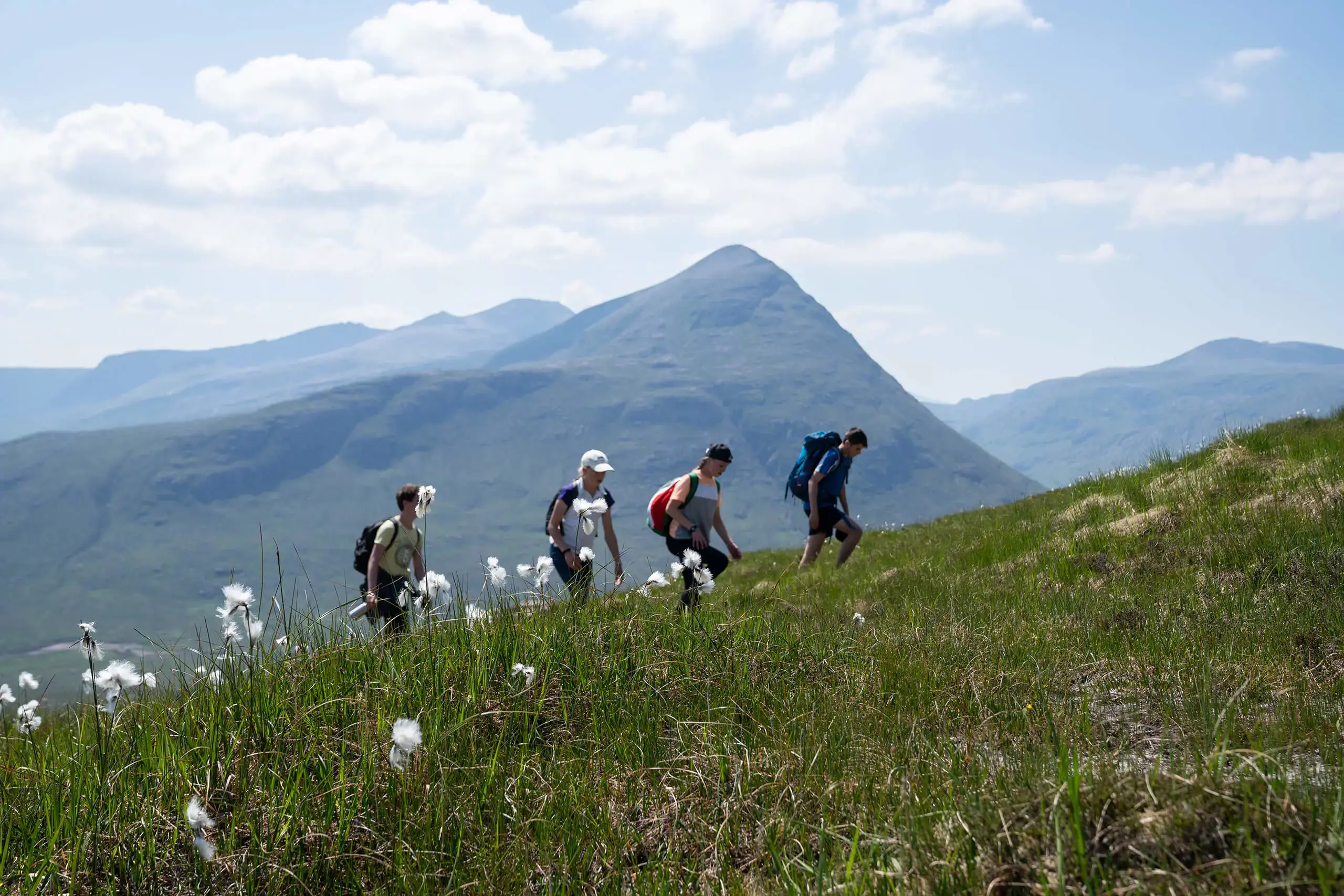 Gordonstoun students on expedition in the Scottish Highlands in the sunshine, with flowers in the foreground.