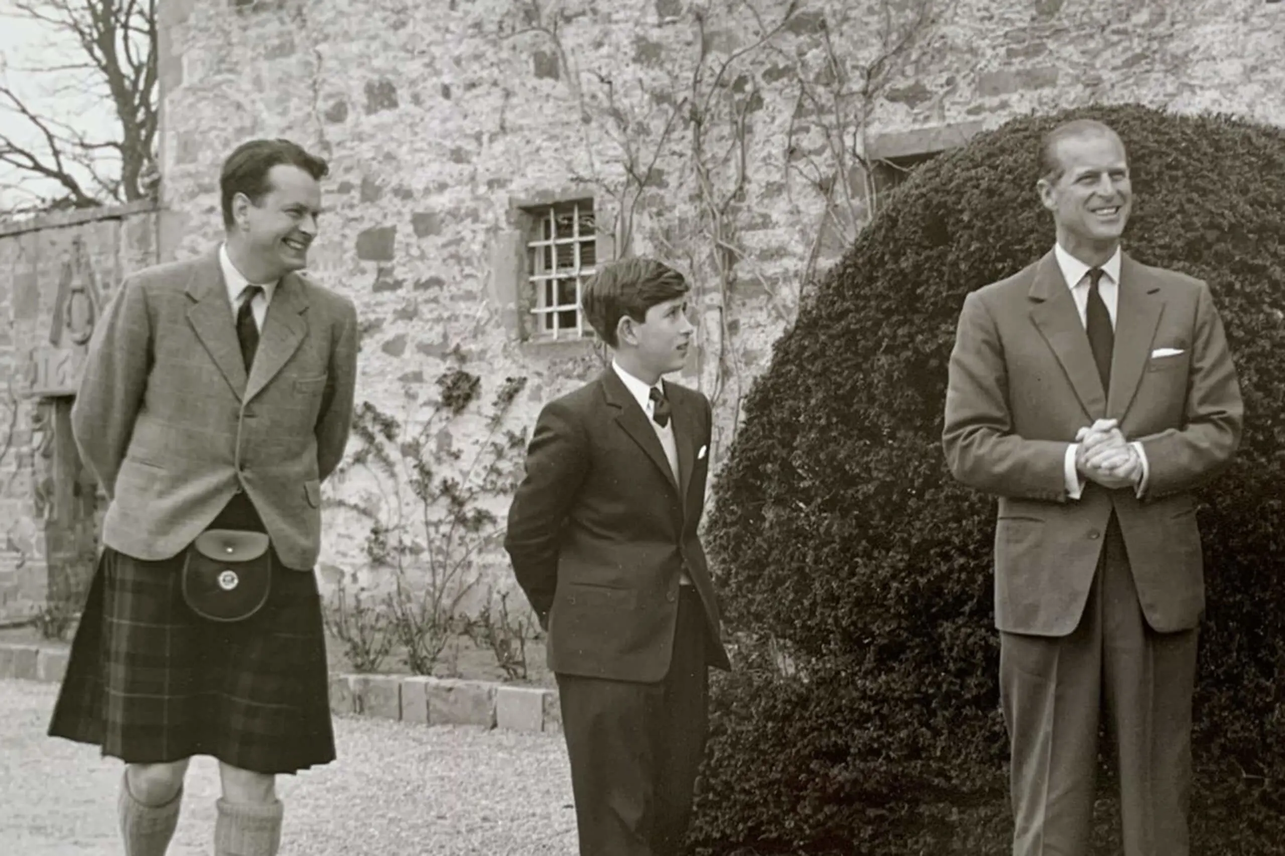 King Charles and Prince Philip walking together outside Gordonstoun. A black and white image.