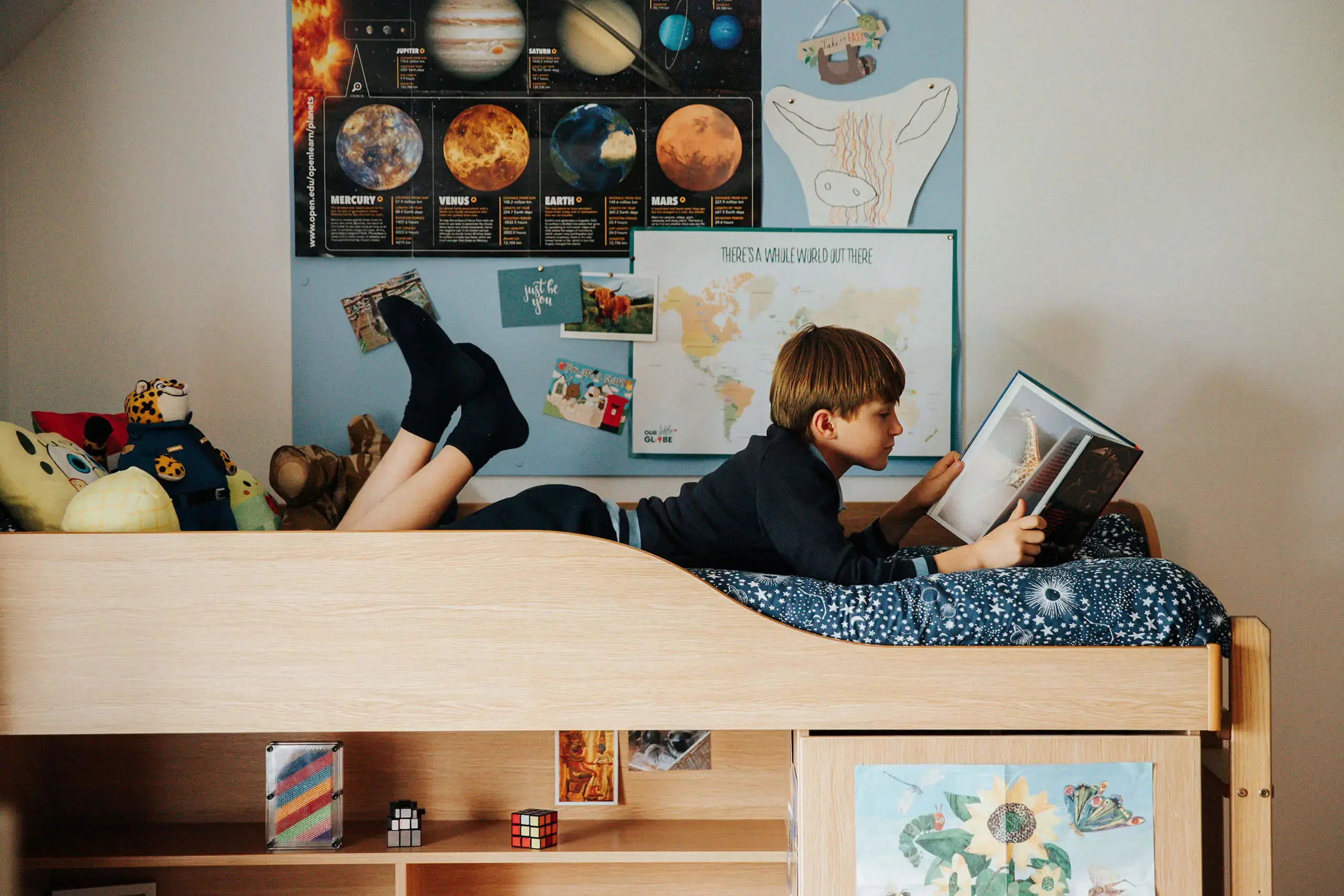 Prep boarder in his bed space that is decorated with posters and cushions and looks homely.