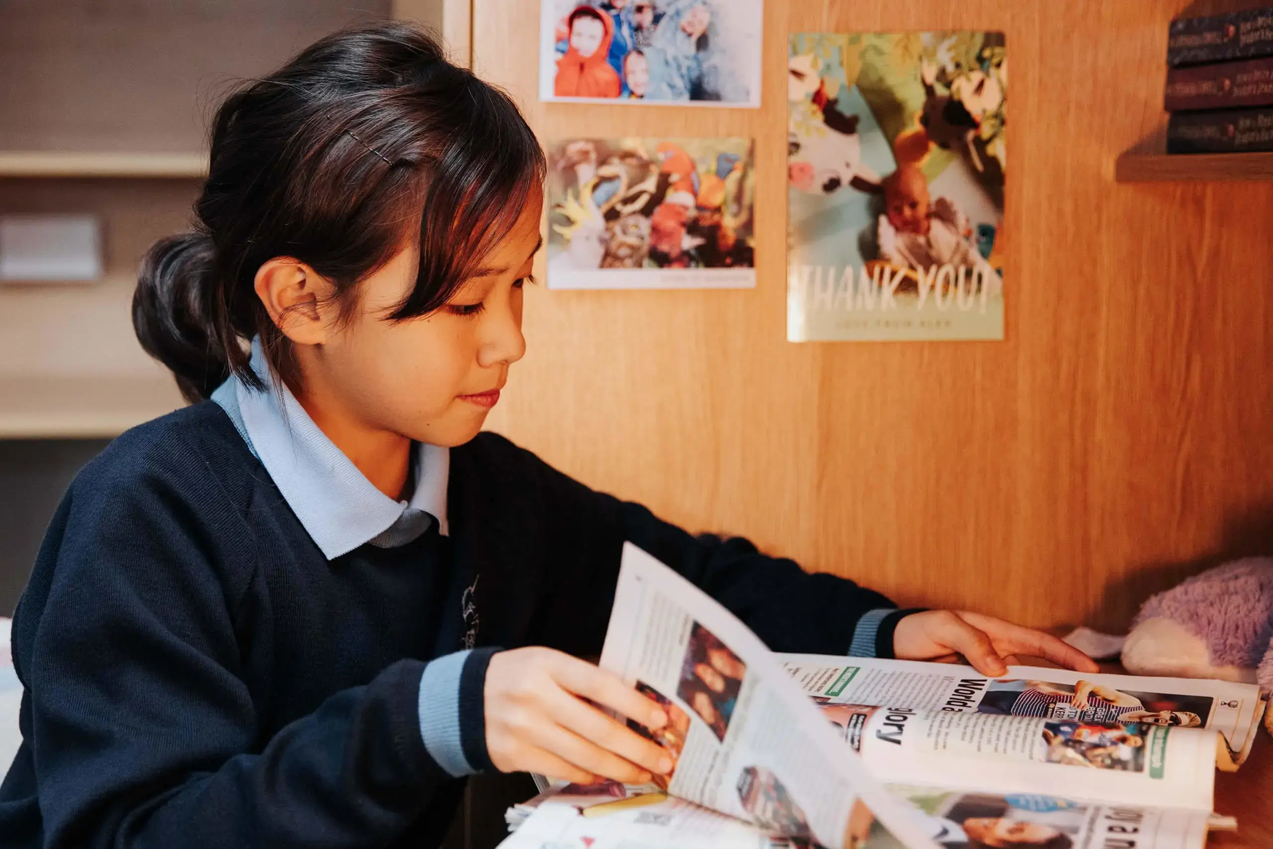 A Chinese pupil studies her magazine at her homely desk within the Prep Boarding House.