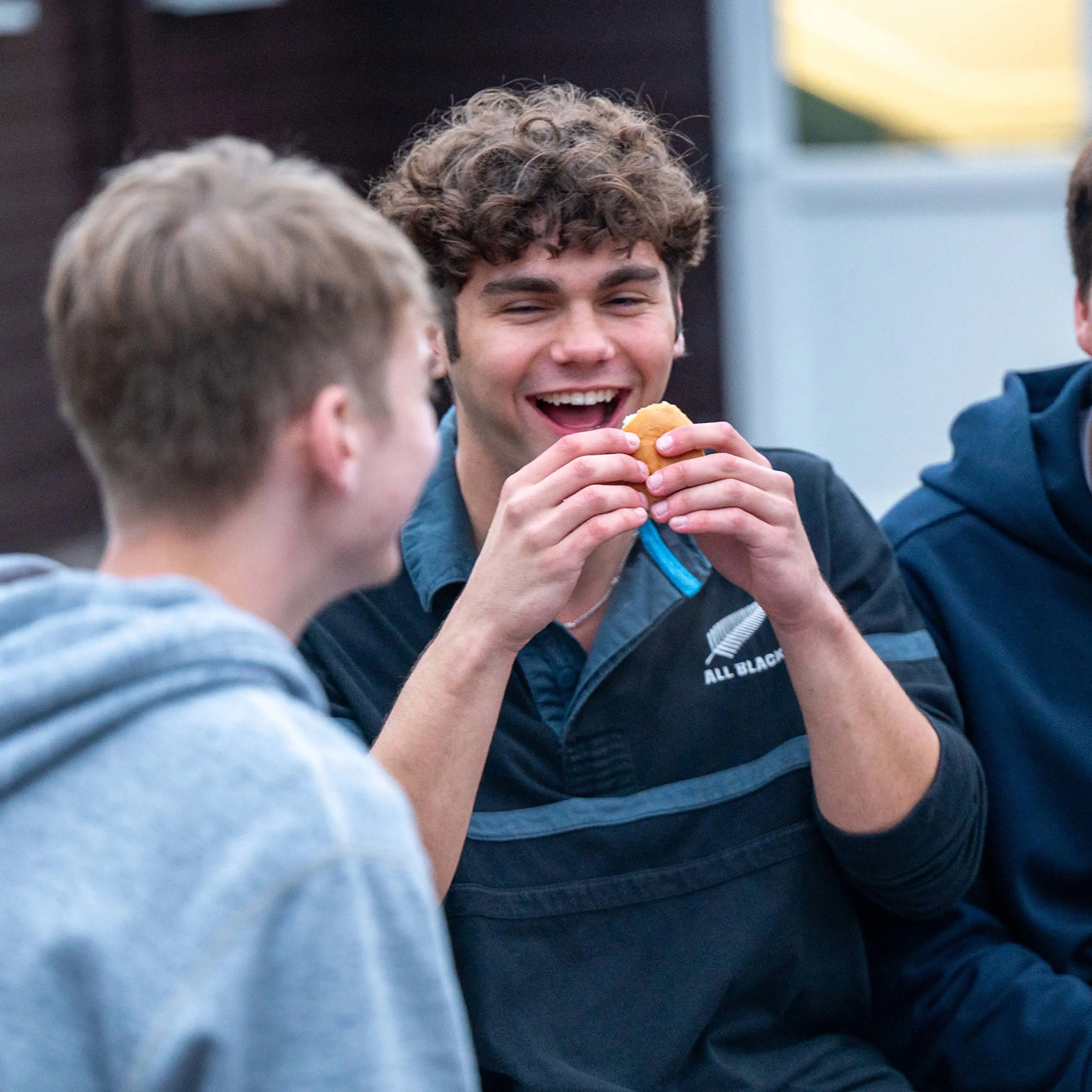 Senior pupil eating a burger, smiling & laughing