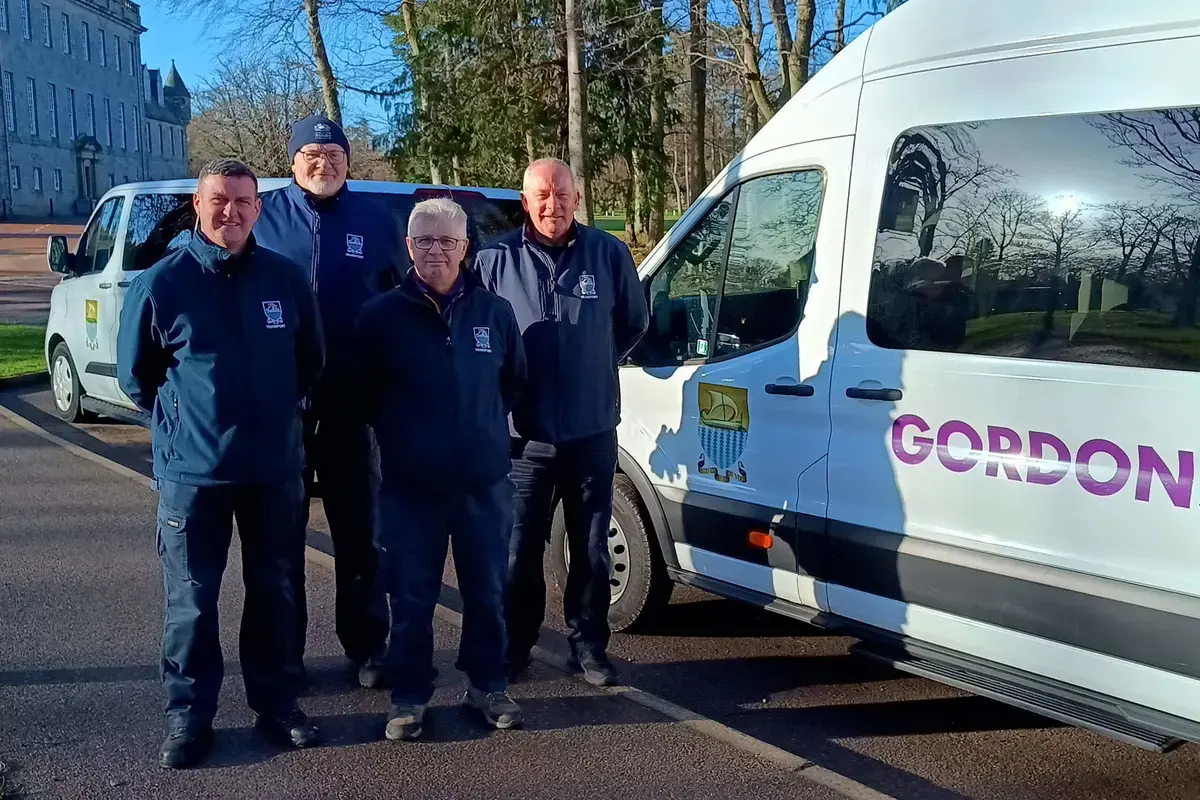 Gordonstoun drivers stand proudly in front of one of the school’s minibuses in the sunshine.